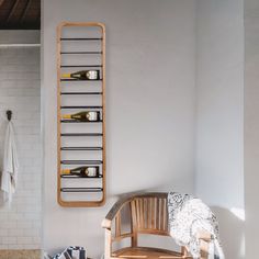 a wooden bench sitting in front of a white tiled wall next to a towel rack