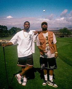 two men standing next to each other on top of a green field