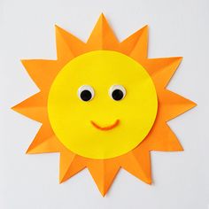 a paper sun with two eyes and one eye on the side, sitting on a white surface