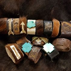 several different bracelets are laid out on a fur surface, including one with turquoise stones and the other with arrows