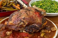 a large piece of meat sitting on top of a white plate filled with vegetables and sauce