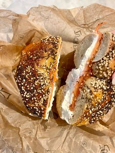 a person holding a sandwich in their hand with sesame seeds on the wrapper next to it