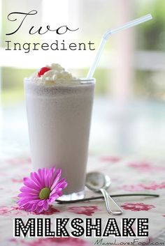 there is a milkshake with whipped cream and a flower on the table next to it