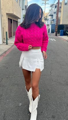 a woman wearing white boots and a pink sweater