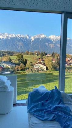 a bed with a blanket on top of it in front of a window overlooking mountains