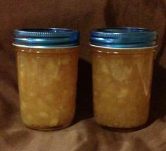 two jars filled with food sitting on top of a brown cloth covered bed next to each other