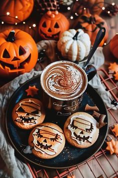 a plate with cookies and pumpkins on it next to a cup of hot chocolate