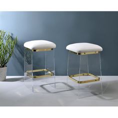 two white stools sitting next to each other in front of a potted plant