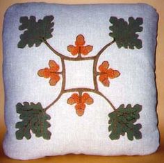 an embroidered pillow with leaves and acorns on the front, sitting on a table