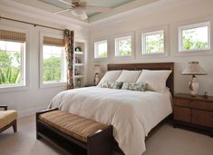 a bedroom with a bed, two chairs and a ceiling fan in it's corner