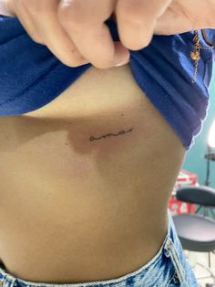 a woman's stomach with the word love tattooed on her lower side ribcage