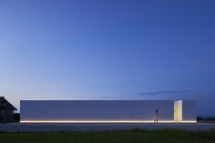 a person standing in front of a large white building at night with the lights on