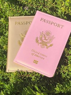 two pink and white passports sitting on top of green grass with the words passport printed on them