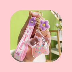 a person holding a pink keychain with a flower on it and a butterfly