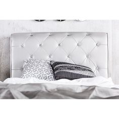 a bed with white leather headboard and pillows on it's sides, in front of two mirrors