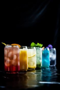 four glasses filled with different colored drinks