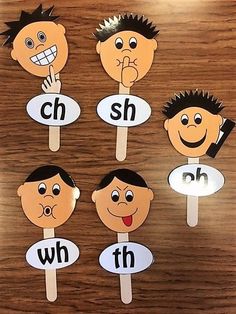 four children's faces on wooden sticks with the word h and w in them