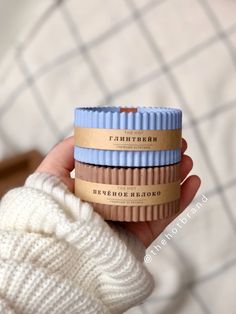 three different colored cups are held in someone's hand, one is white and the other is blue