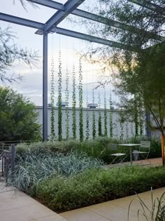 an outdoor dining area with tables and chairs, surrounded by greenery at the back