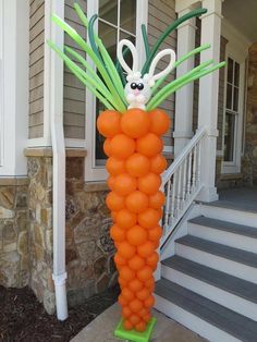 an orange balloon sculpture with carrots on it in front of a house and steps