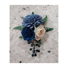 a blue and white flower with green leaves on a marble surface in front of the camera