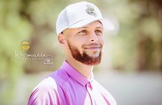 a man with a beard wearing a pink shirt and white hat smiling at the camera