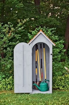 an outhouse with gardening tools in it sitting on the grass next to some trees