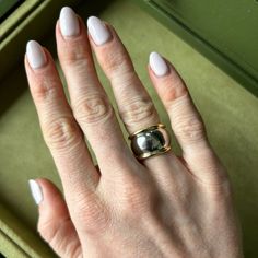 a woman's hand with white nails and a gold ring