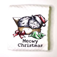 a white dish towel with a cat sleeping on it's side and merry christmas written across the front