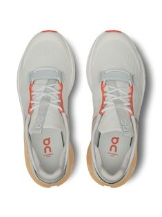 a pair of white sneakers with orange laces on the bottom and upper part of the shoe