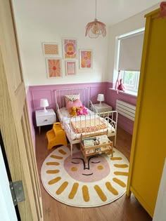 a bedroom with pink and yellow walls, white furniture and a rug on the floor