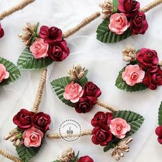 many red and pink flowers are placed on some rope with green leafy leaves around them