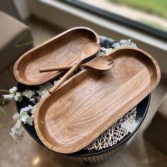 two wooden serving trays sitting on top of a table next to a flower vase