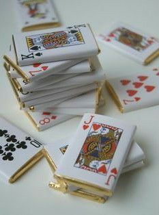 a stack of playing cards sitting on top of a table next to some gold pins