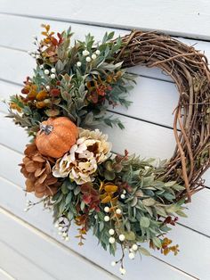 a wreath is hanging on the side of a building with flowers and leaves around it