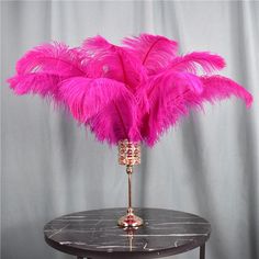 a vase with pink feathers on a table