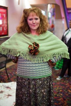 a woman standing in a room wearing a green shawl