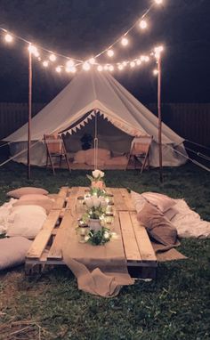 a table with candles on it sitting in the middle of a field next to a tent