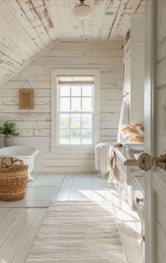 an attic bathroom with white walls and wood flooring, along with a rug on the floor