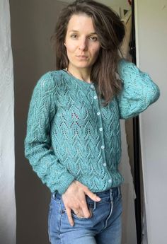 a woman is standing in front of a door wearing a green sweater and blue jeans