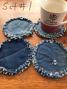 four denim coasters sitting on top of a wooden table next to a coffee cup