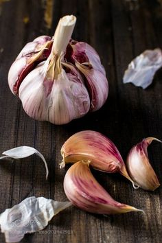 garlic on a wooden table next to an onion peel