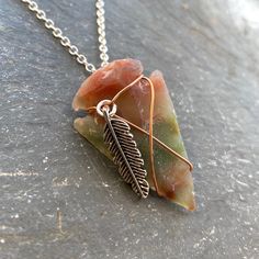 "This minimalist copper wire-wrapped arrowhead necklace is accompanied by a small silver-toned feather charm. Made of agate or Jasper, copper, silver-plated chain, and a matching lobster clasp. Arrowhead measures approximately 1.5\" (one and a half inches) in length. Arrowheads vary slightly in size, shape and color. Each will have sight variations in texture and wire wrapping to accommodate individual characteristics. It can be worn alone or layered for a modern boho look. Looking for a wellnes Handmade Sterling Silver Arrowhead Necklace, Bohemian Arrowhead Jewelry As Gift, Bohemian Arrowhead Jewelry As A Gift, Bohemian Arrowhead Jewelry Gift, Arrowhead Wire Wrapped Necklaces For Gifts, Unique Handmade Arrowhead Necklaces, Adjustable Wire Wrapped Arrowhead Necklace, Unique Handmade Arrowhead Necklace, Artisan Arrowhead Necklace For Gift