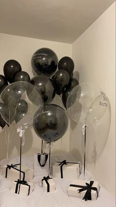 black and white balloons are in the shape of gifts on a bed with ribbons tied around them