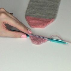 a woman is knitting with her hands and the needles are on top of the knitted mitt