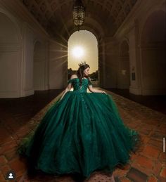 a woman in a green ball gown sitting on the floor with her back to the camera