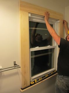 a man working on a window in a room that is being built into the wall