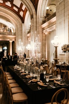 an elegant dining room set up with black table cloths and tall centerpieces