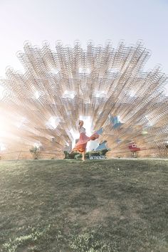 a person standing on top of a grass covered field next to a large metal object