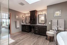 a large bathroom with wooden floors and gray walls, along with a white bathtub